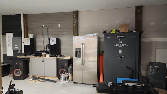 kitchen with white cabinetry, stainless steel fridge with ice dispenser, and wood walls