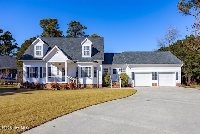 new england style home featuring a garage, covered porch, and a front lawn