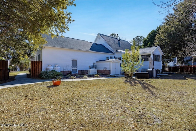 rear view of house featuring a shed, central AC unit, a yard, and a sunroom