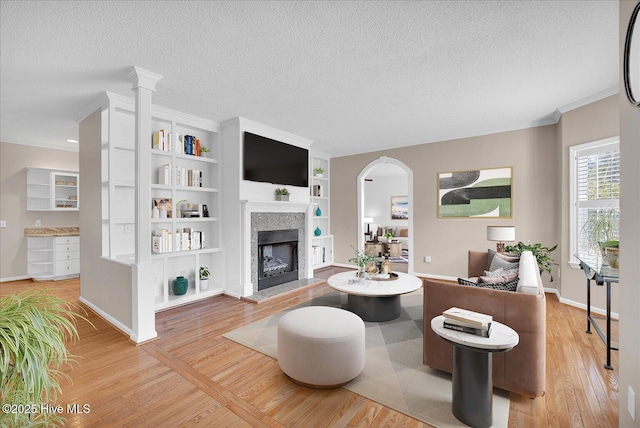 living room featuring hardwood / wood-style flooring, ornamental molding, built in features, and a textured ceiling