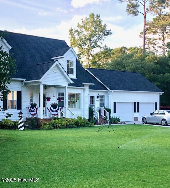 view of front of house featuring a garage, a porch, and a front lawn