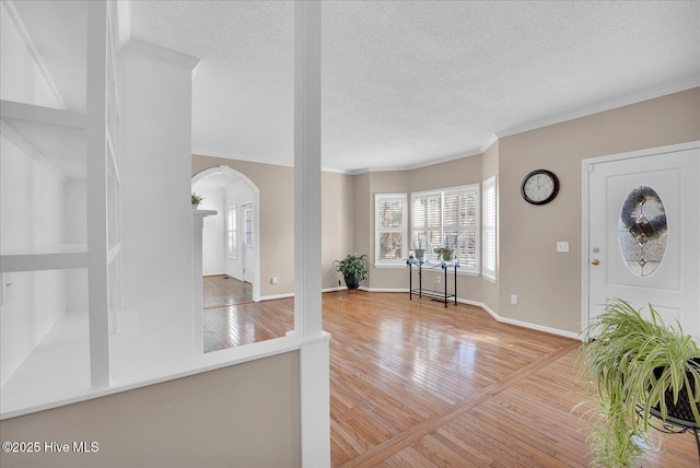 foyer featuring crown molding, light hardwood / wood-style flooring, and a textured ceiling