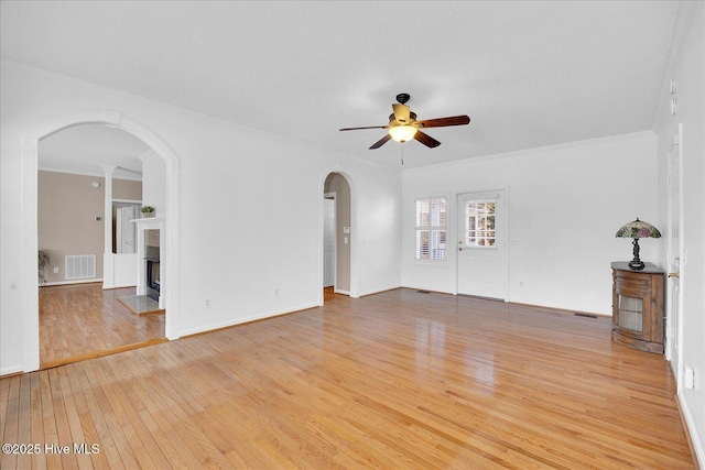 unfurnished living room with crown molding, wood-type flooring, and ceiling fan