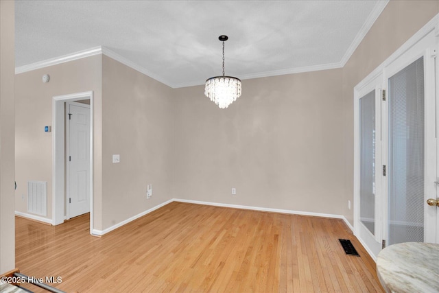 spare room featuring ornamental molding, an inviting chandelier, and light wood-type flooring