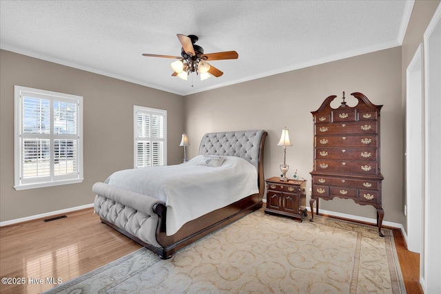 bedroom with ceiling fan, ornamental molding, light hardwood / wood-style flooring, and a textured ceiling