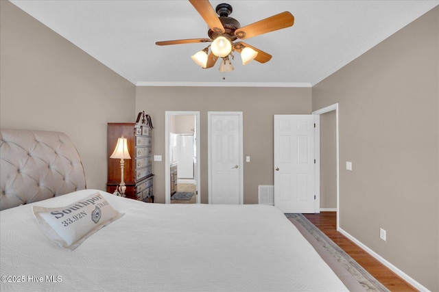 bedroom with connected bathroom, ornamental molding, dark hardwood / wood-style floors, and ceiling fan