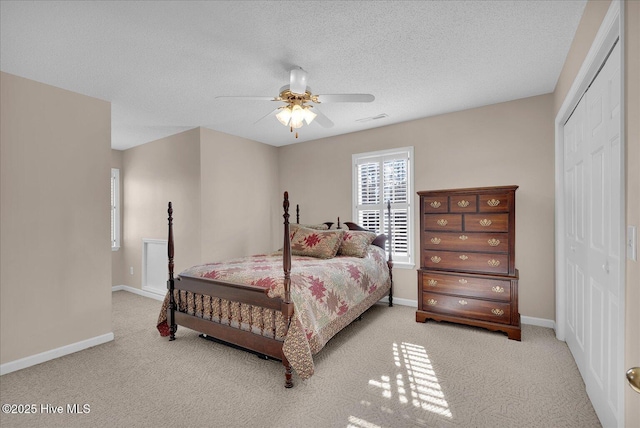 bedroom with ceiling fan, light colored carpet, a closet, and a textured ceiling