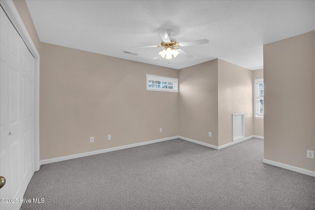 carpeted spare room with plenty of natural light, a textured ceiling, and ceiling fan