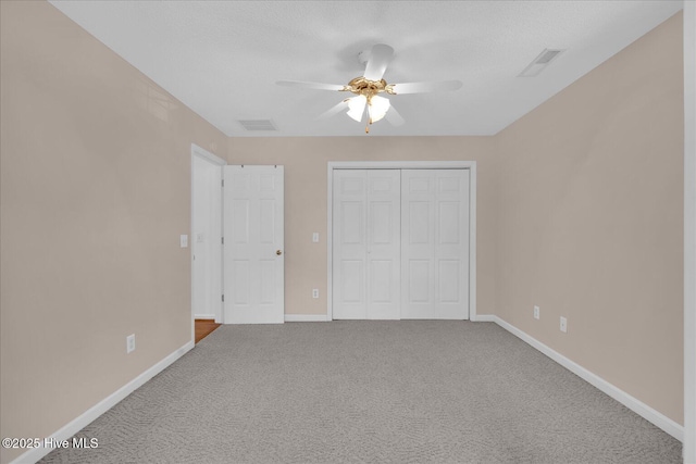 unfurnished bedroom with ceiling fan, carpet flooring, a closet, and a textured ceiling