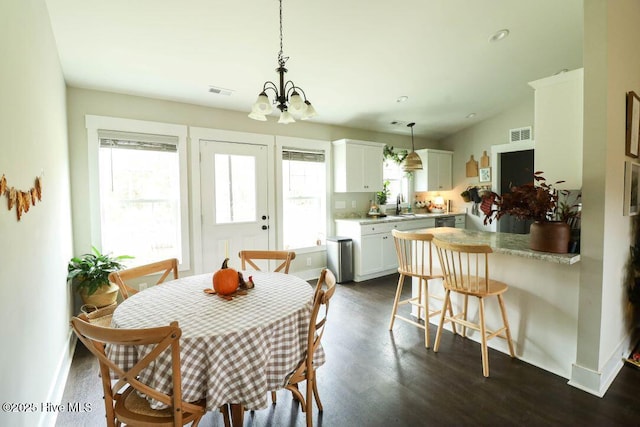 dining room featuring dark wood-type flooring, a chandelier, and sink