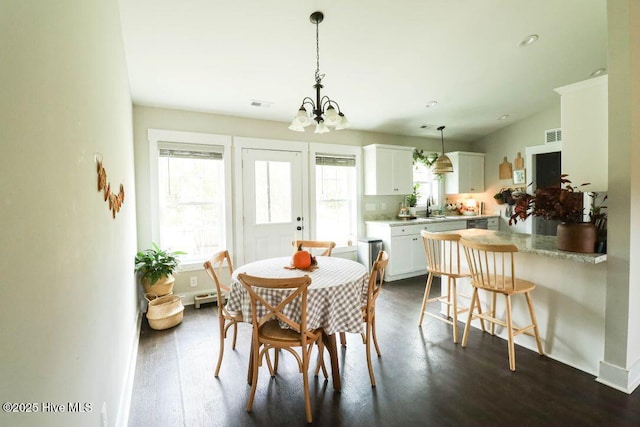 dining room featuring sink, dark wood-type flooring, and a chandelier