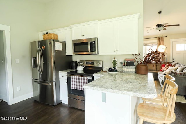 kitchen featuring white cabinetry, dark hardwood / wood-style flooring, a breakfast bar area, and appliances with stainless steel finishes