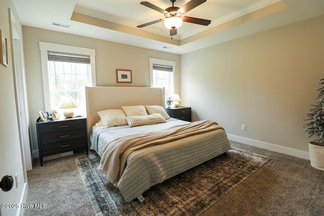 bedroom with crown molding, ceiling fan, dark carpet, and a tray ceiling