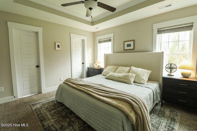 bedroom with ceiling fan, ornamental molding, a raised ceiling, and dark carpet