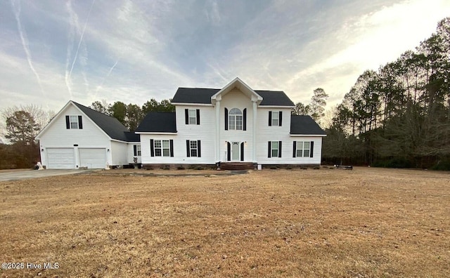 colonial home with a garage and a front lawn