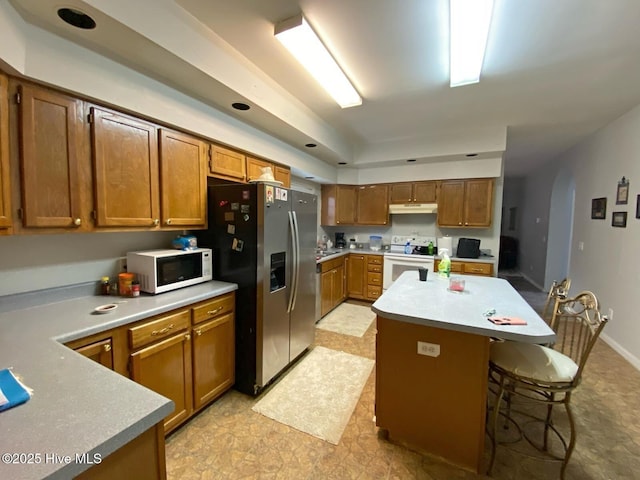 kitchen with white appliances, a breakfast bar area, and a center island