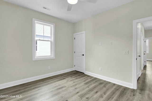 spare room featuring a ceiling fan, wood finished floors, baseboards, and visible vents