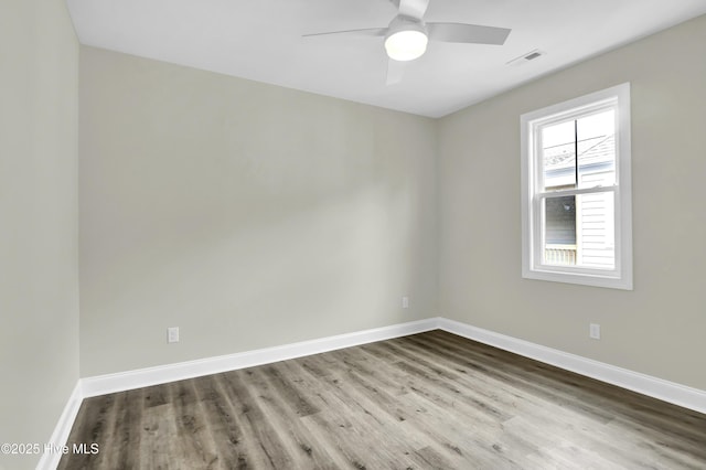 spare room featuring visible vents, baseboards, wood finished floors, and a ceiling fan