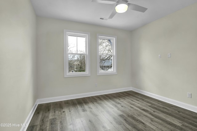 empty room with dark wood finished floors, visible vents, baseboards, and ceiling fan