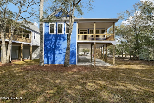 back of property with a carport, a yard, and ceiling fan