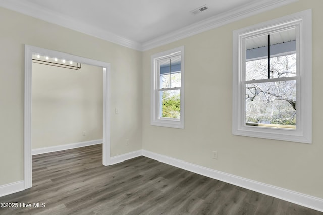 empty room featuring dark wood-style floors, visible vents, baseboards, and ornamental molding