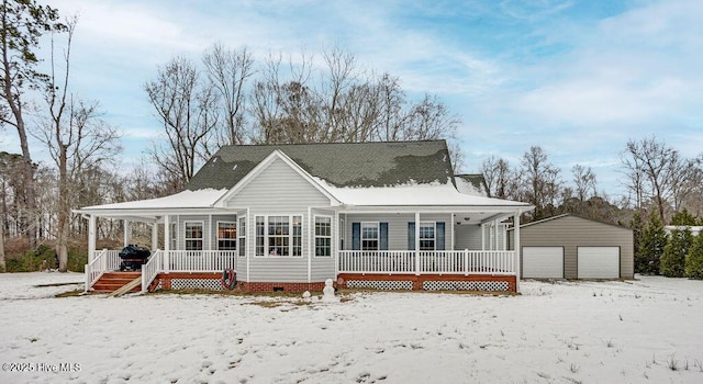 snow covered back of property with an outbuilding, a garage, and a porch