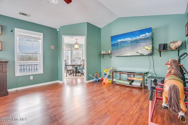 game room with lofted ceiling, a textured ceiling, wood-type flooring, and ceiling fan