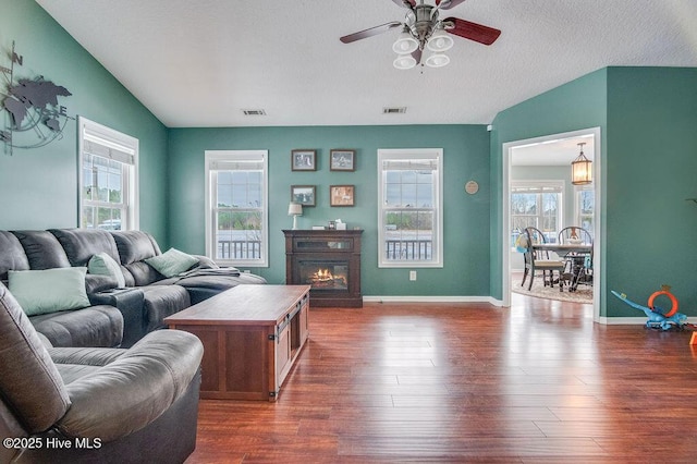 living room featuring ceiling fan, plenty of natural light, a textured ceiling, and dark hardwood / wood-style flooring