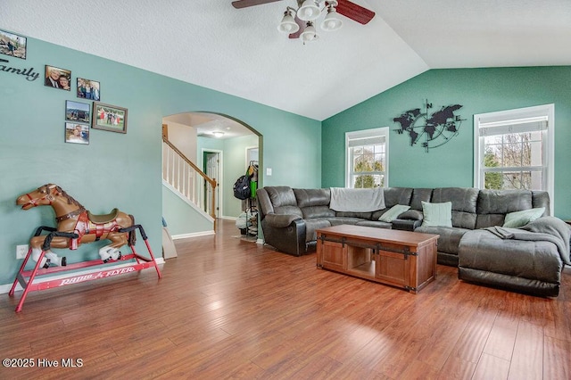 living room with ceiling fan, wood-type flooring, and vaulted ceiling