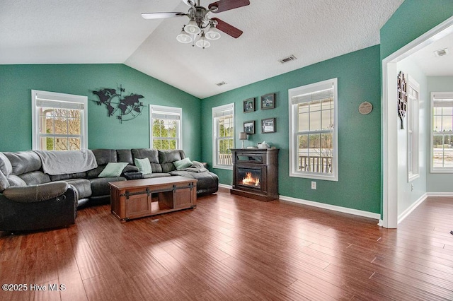 living room with ceiling fan, dark hardwood / wood-style flooring, vaulted ceiling, and a textured ceiling