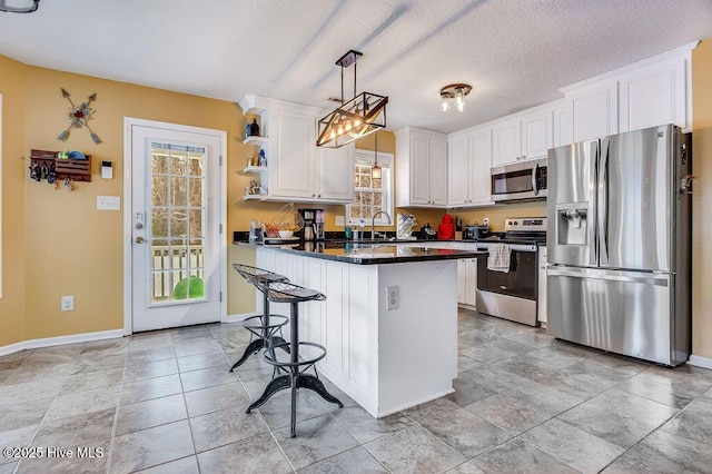 kitchen featuring pendant lighting, sink, appliances with stainless steel finishes, dark stone countertops, and white cabinets