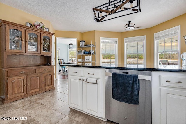 kitchen featuring white cabinetry, light tile patterned floors, stainless steel dishwasher, and a textured ceiling