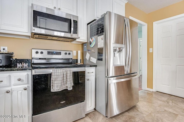 kitchen featuring dark stone counters, white cabinets, and appliances with stainless steel finishes