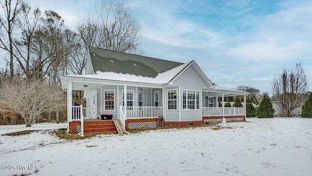 snow covered back of property with covered porch