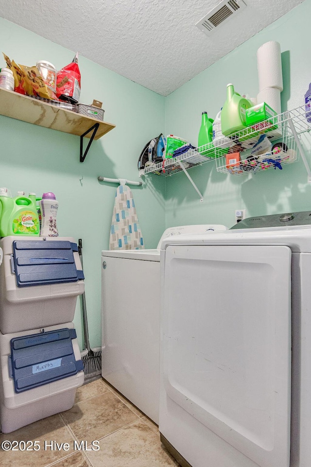 laundry room with light tile patterned floors, washer and dryer, and a textured ceiling