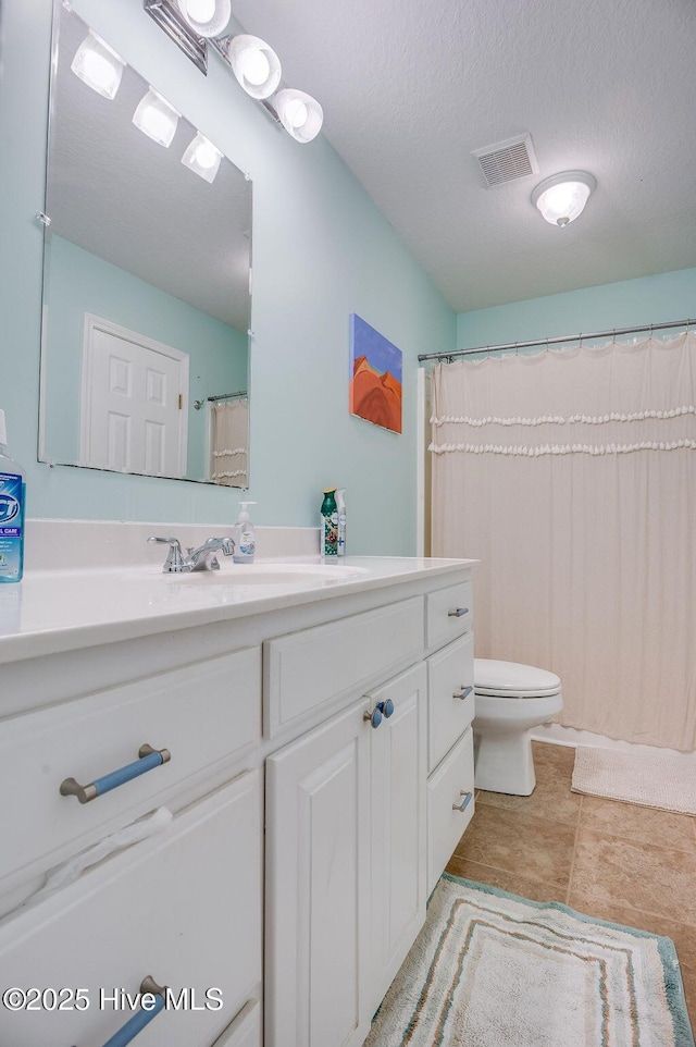 bathroom with vanity, toilet, tile patterned flooring, and a textured ceiling