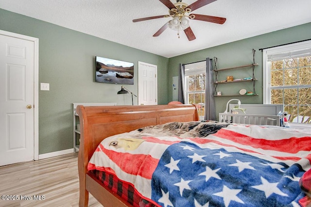 bedroom with ceiling fan, a textured ceiling, and light wood-type flooring