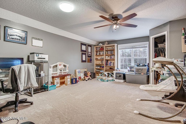 game room with a textured ceiling, ceiling fan, and carpet flooring