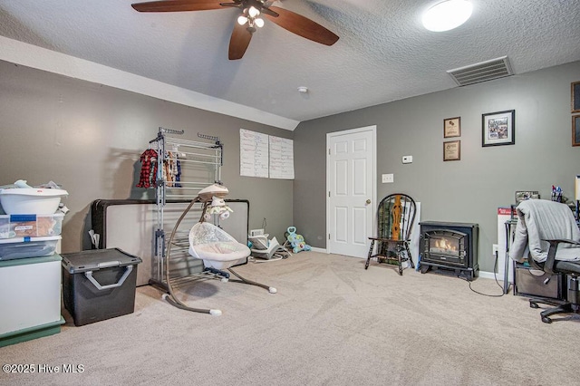 exercise room featuring a wood stove, a textured ceiling, and carpet flooring