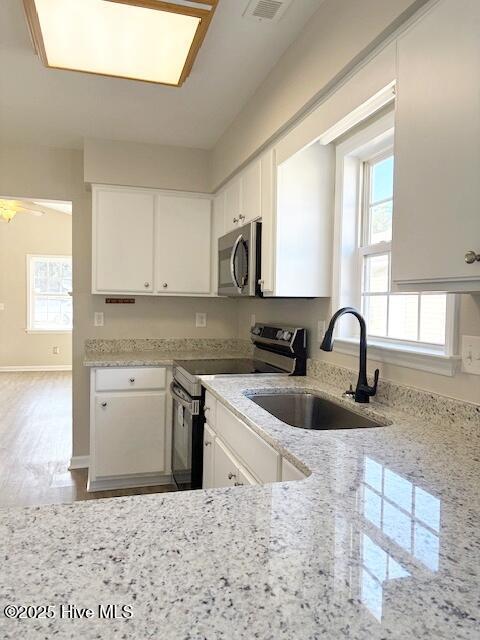 kitchen featuring white cabinetry, light stone countertops, stainless steel appliances, and sink