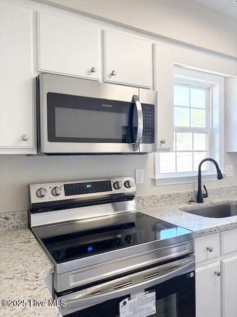 kitchen featuring light stone counters, sink, white cabinets, and appliances with stainless steel finishes