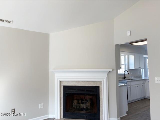 interior details with a tiled fireplace, hardwood / wood-style flooring, and sink