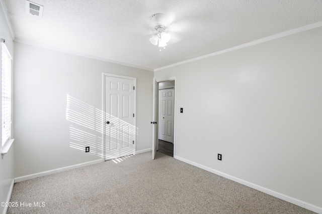 carpeted spare room with ceiling fan, ornamental molding, and a textured ceiling