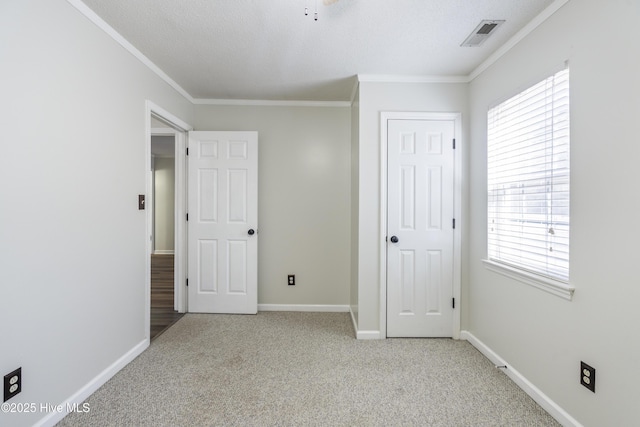 unfurnished bedroom with light colored carpet, ornamental molding, and a textured ceiling