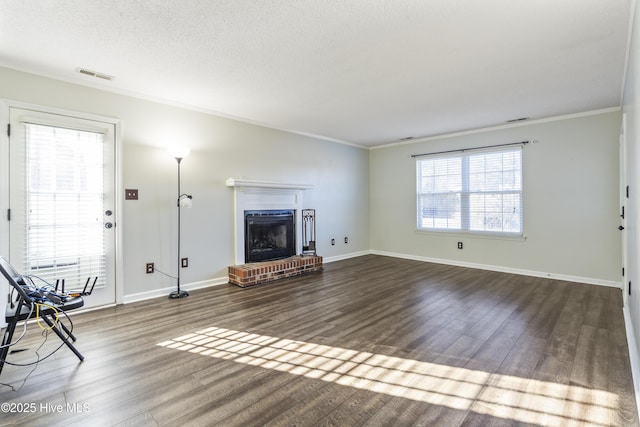 unfurnished living room featuring ornamental molding, wood-type flooring, a brick fireplace, and a textured ceiling