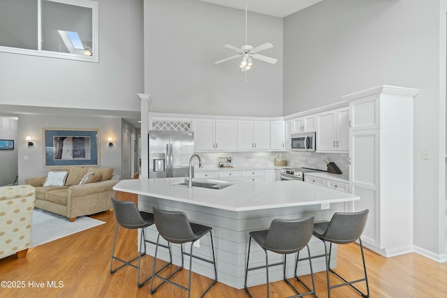 kitchen with stainless steel appliances, white cabinetry, sink, and a kitchen breakfast bar