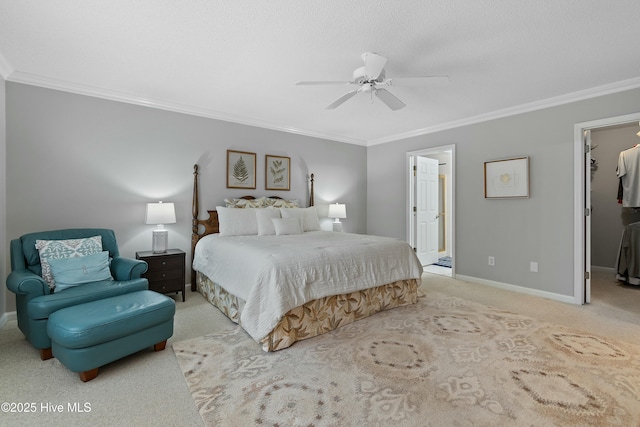 bedroom featuring a walk in closet, light colored carpet, ceiling fan, crown molding, and ensuite bath