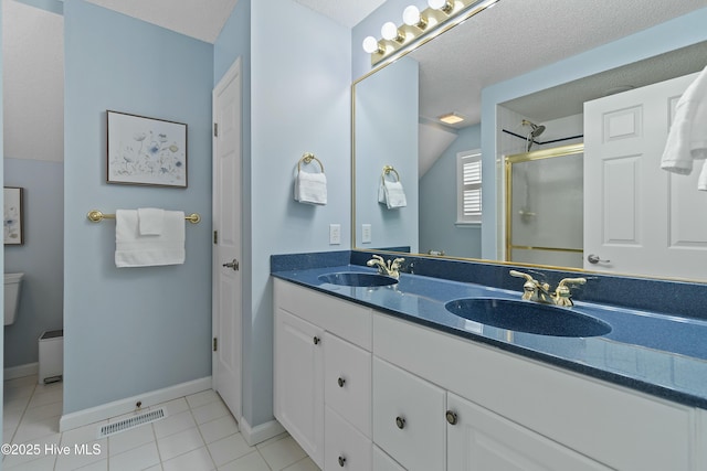 bathroom featuring a shower with door, vanity, a textured ceiling, tile patterned floors, and toilet