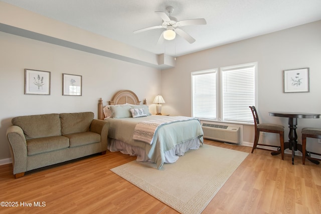 bedroom featuring a wall mounted air conditioner, ceiling fan, and light hardwood / wood-style flooring