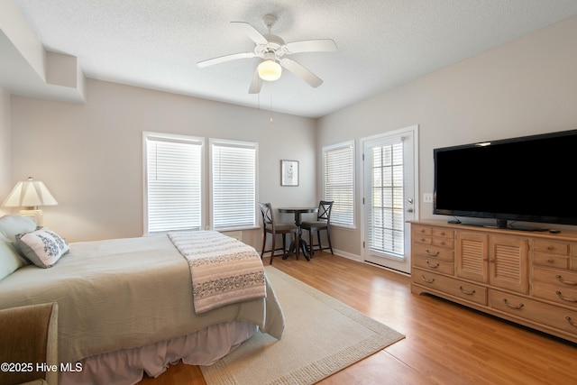 bedroom featuring hardwood / wood-style flooring, ceiling fan, access to outside, and a textured ceiling